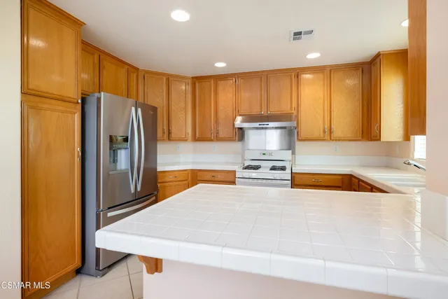 a kitchen with stainless steel appliances granite countertop a refrigerator a stove and a sink