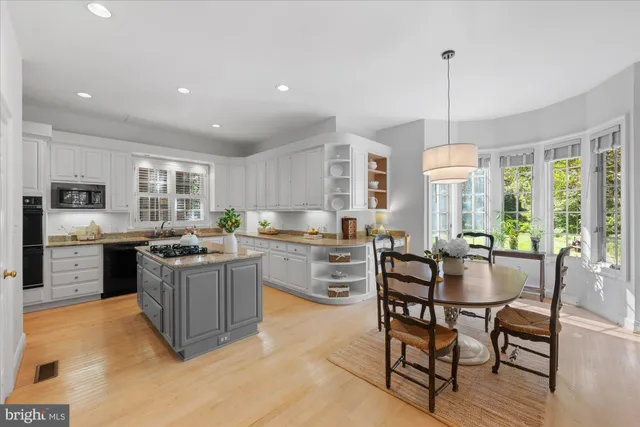 a kitchen with stainless steel appliances granite countertop a stove top oven a sink dishwasher a dining table and chairs with wooden floor