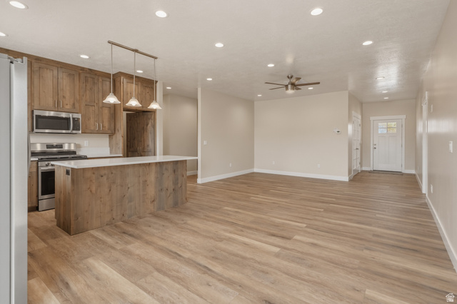 157 West 100 South Joseph, UT 84739 - Photo 8 of 30 Kitchen featuring stainless steel appliances, decorative light fixtures, wood finish cabinets, a kitchen island, and light wood finished floors