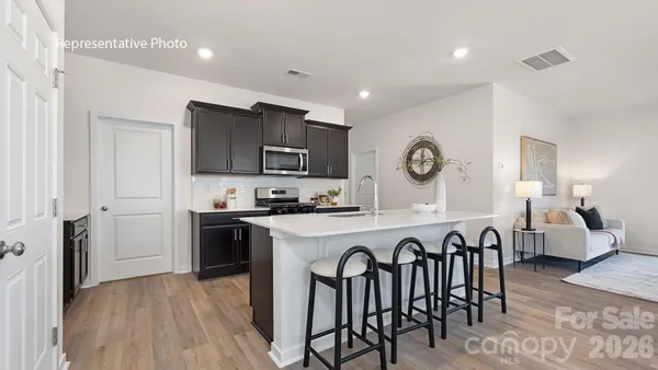 a kitchen with stainless steel appliances granite countertop a refrigerator a stove top oven a sink dishwasher and white cabinets with wooden floor
