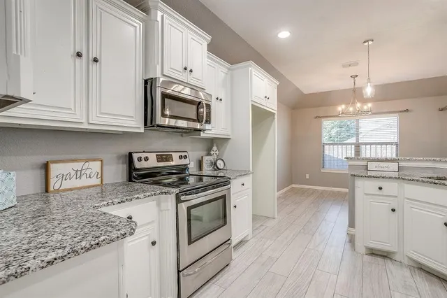 a kitchen with stainless steel appliances granite countertop a sink a stove and a wooden floors