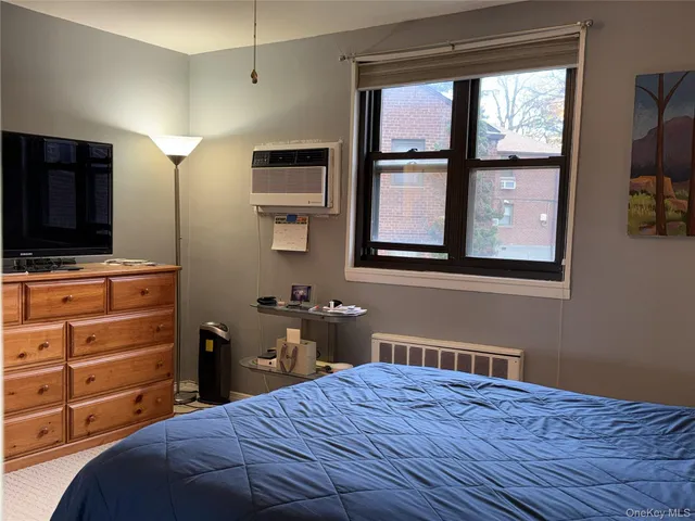 a bedroom with a bed and a flat tv screen on dresser