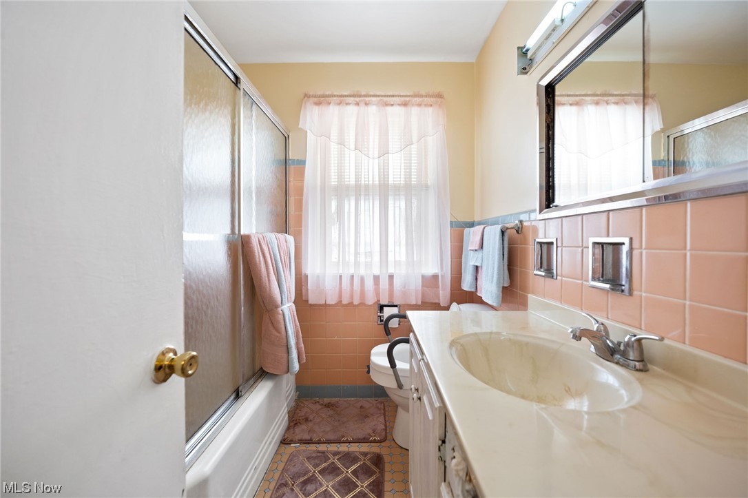 4170 Stilmore Road Cleveland, OH 44121 - Photo 19 of 26 Full bathroom featuring tile floors, combined bath / shower with glass door, a wealth of natural light, and oversized vanity