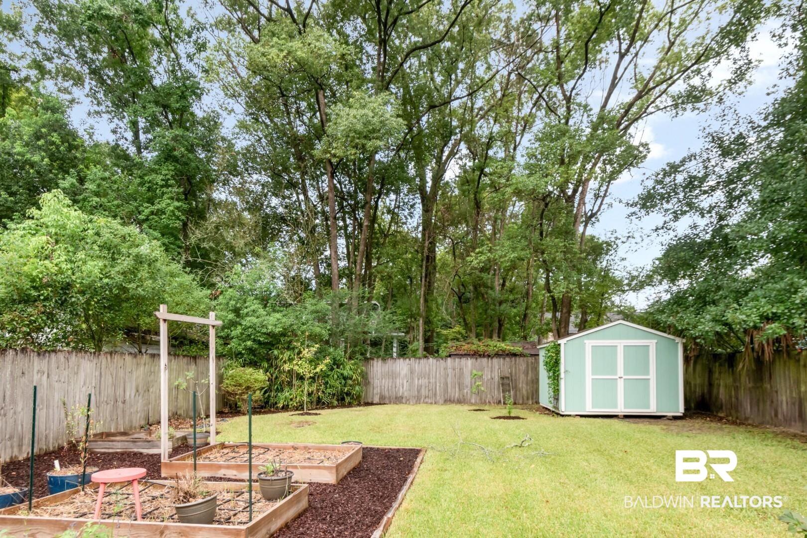 14 Kenneth Street Mobile, AL 36607 - Photo 28 of 32 Fenced backyard featuring a vegetable garden and a storage unit