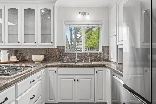 a kitchen with granite countertop white cabinets and window