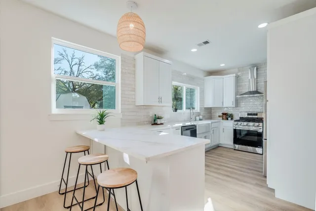 a kitchen with kitchen island a large window cabinets and stainless steel appliances