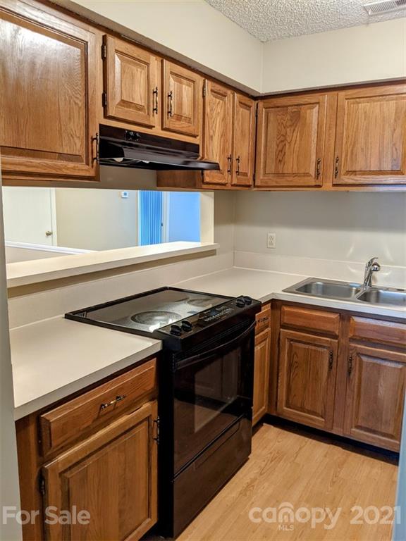 1608 Sharon Road West, Unit 48 Charlotte, NC 28210 - Photo 6 of 15 a kitchen with granite countertop a stove top oven a sink dishwasher and cabinets with wooden floor