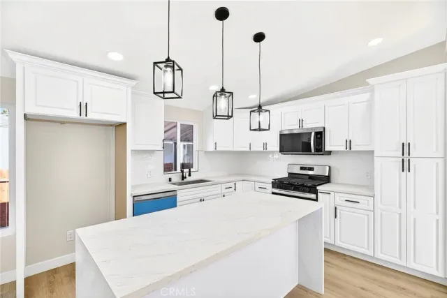 a kitchen with stainless steel appliances a stove a sink and white cabinets