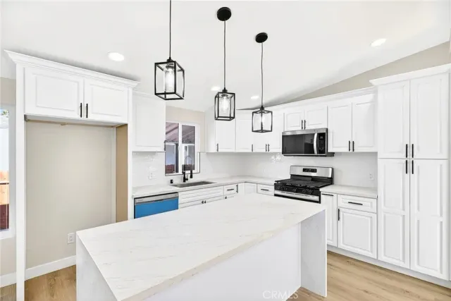 a kitchen with stainless steel appliances a stove a sink and white cabinets