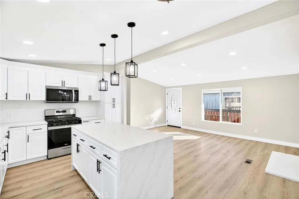80 Dawes, Unit 88 Perris, CA 92571 - Photo 10 of 29 a kitchen with stainless steel appliances kitchen island granite countertop a stove a sink a refrigerator and white cabinets with wooden floor