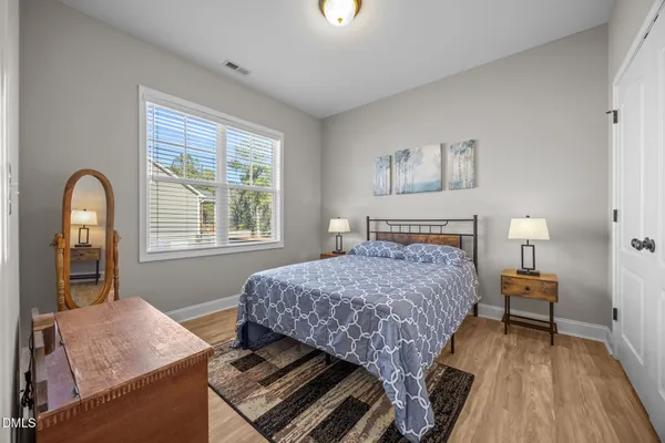 a bedroom with a bed a dresser and a chandelier