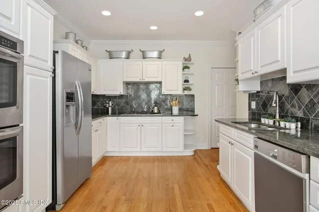 a kitchen with stainless steel appliances a refrigerator sink and white cabinets