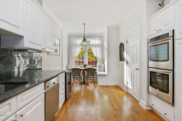 a kitchen with granite countertop stainless steel appliances a stove top oven a sink a dining table and chairs