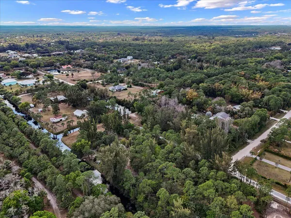 an aerial view of residential houses with outdoor space and trees