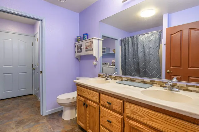 a bathroom with a granite countertop sink a toilet a mirror and shower