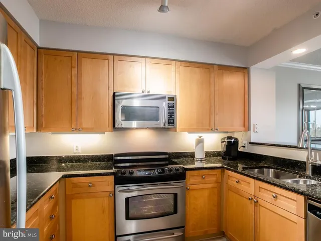 a kitchen with stainless steel appliances granite countertop a stove a sink and a microwave