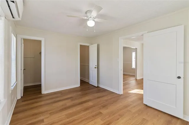 an empty room with wooden floor and a ceiling fan