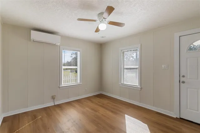 an empty room with wooden floor ceiling fan and windows