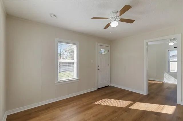 a view of an empty room with window and wooden floor