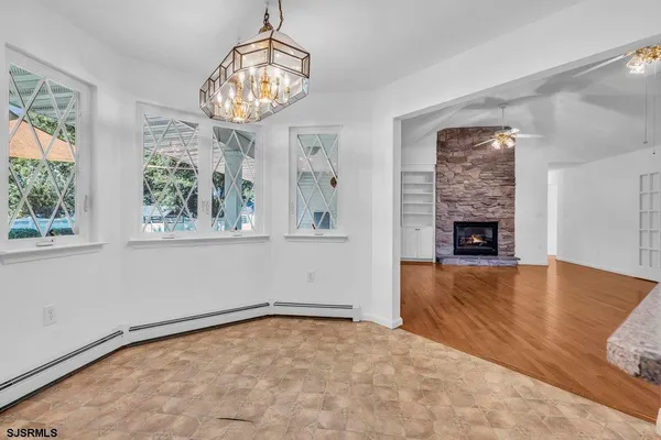 an empty room with wooden floor chandelier fan and windows