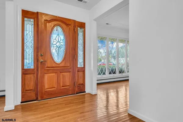 an empty room with wooden floor chandelier fan and windows