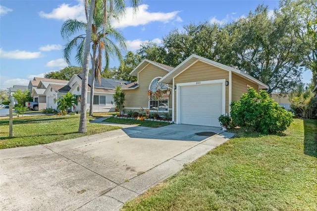 a view of a white house next to a yard with big trees