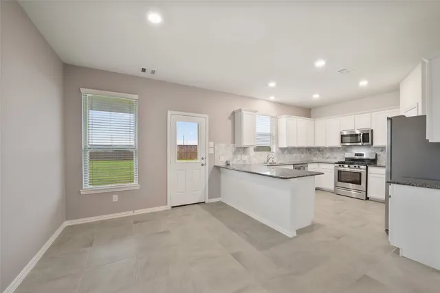 a open kitchen with white cabinets and white appliances