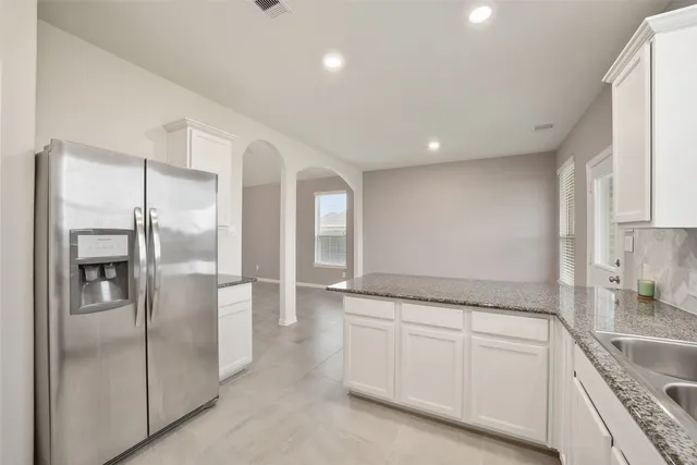 a spacious bathroom with a granite countertop sink and a refrigerator