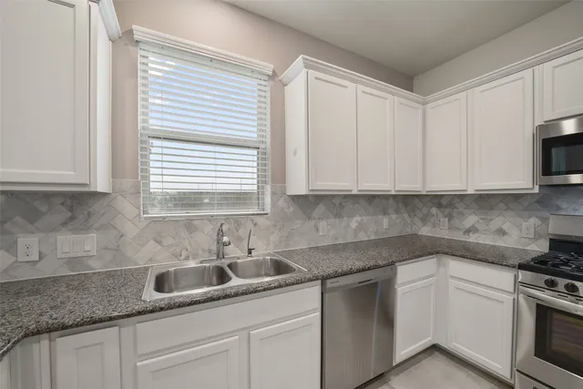 a kitchen with granite countertop white cabinets and white appliances