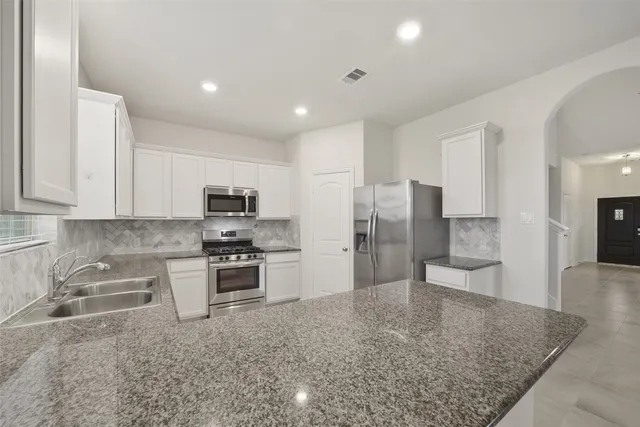 a kitchen with stainless steel appliances granite countertop a sink stove and refrigerator