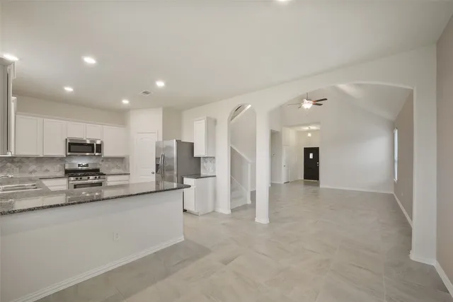 a large white kitchen with stainless steel appliances granite countertop a refrigerator and a stove top oven