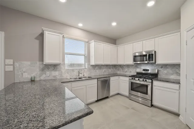 a kitchen with stainless steel appliances granite countertop a stove a sink and a microwave