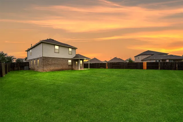 a view of a big house with a big yard and large trees