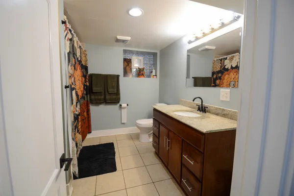 a spacious bathroom with a double vanity sink a toilet a mirror and shower