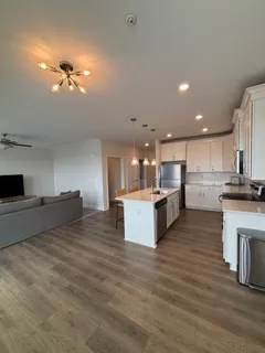 a large kitchen with a large counter top a sink stainless steel appliances and cabinets