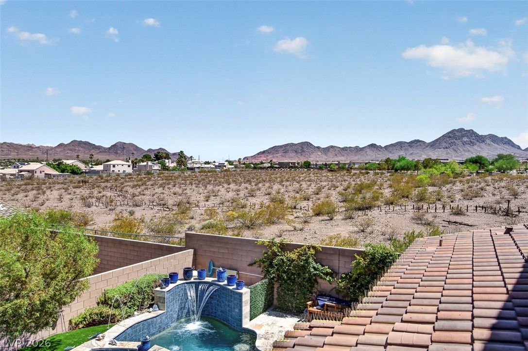 1824 Redland Ridge Street Henderson, NV 89002 - Photo 46 of 69 A private pool with a waterfall feature offers a refreshing oasis amidst a rugged desert landscape with distant mountains.