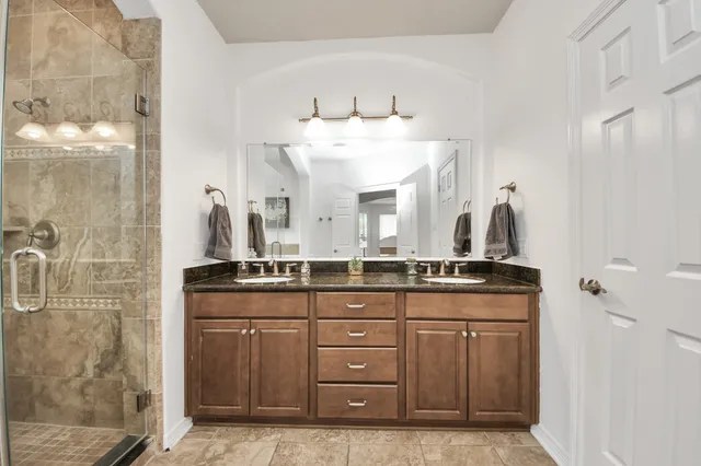 a bathroom with a granite countertop sink a mirror and a shower