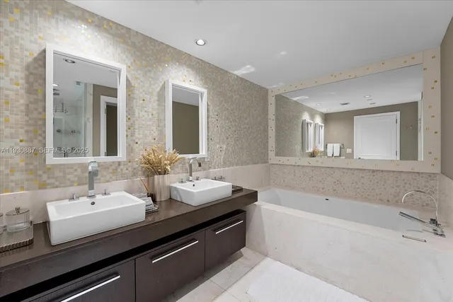 a bathroom with a double vanity sink and mirror with bathtub
