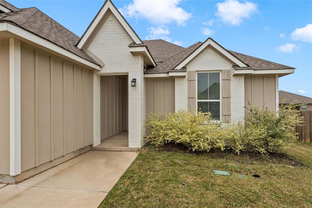 3208 Dottavio Road Lorena, TX 76655 - Photo 3 of 31 Exterior featuring a combination of cream-painted brick and vertical tan siding, a brown asphalt shingle roof, decorative window shutters, and an entry porch light fixture