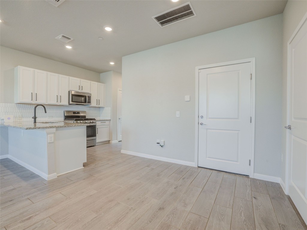 9015 Cattle Baron Path, Unit 502 Austin, TX 78747 - Photo 10 of 40 a kitchen with granite countertop white cabinets and stainless steel appliances