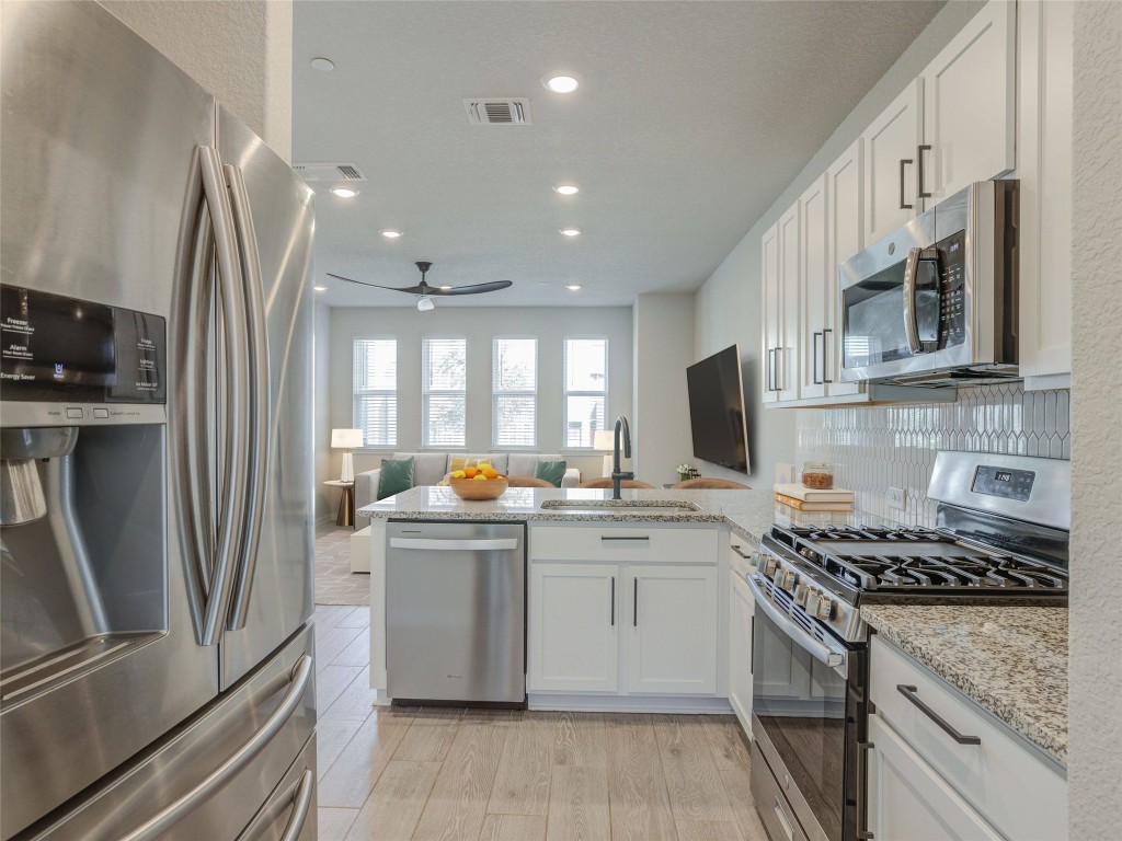 9015 Cattle Baron Path, Unit 502 Austin, TX 78747 - Photo 40 of 40 a kitchen with stainless steel appliances granite countertop a stove top oven a sink a refrigerator and white cabinets