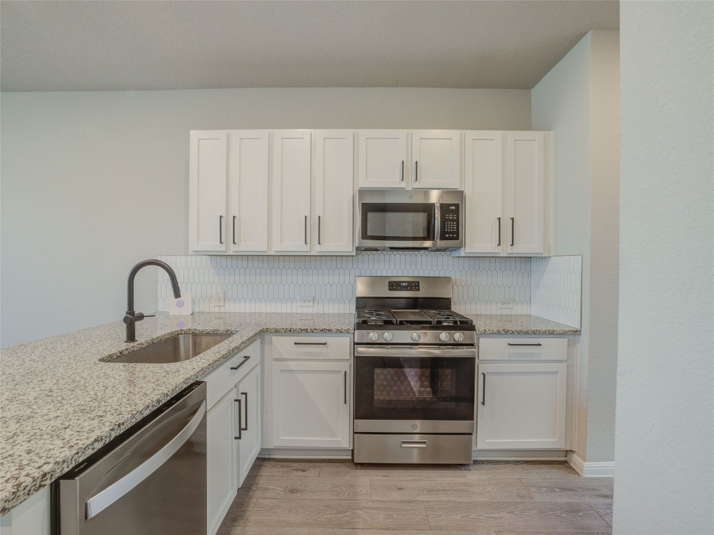 9015 Cattle Baron Path, Unit 502 Austin, TX 78747 - Photo 30 of 40 a kitchen with white cabinets stainless steel appliances and sink