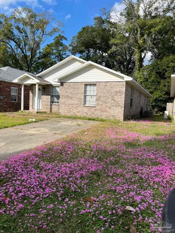 a view of a white house with a yard and garden