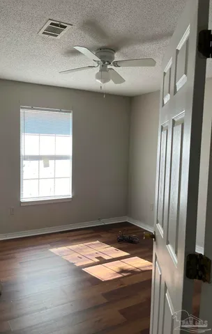 a view of empty room with wooden floor and fan