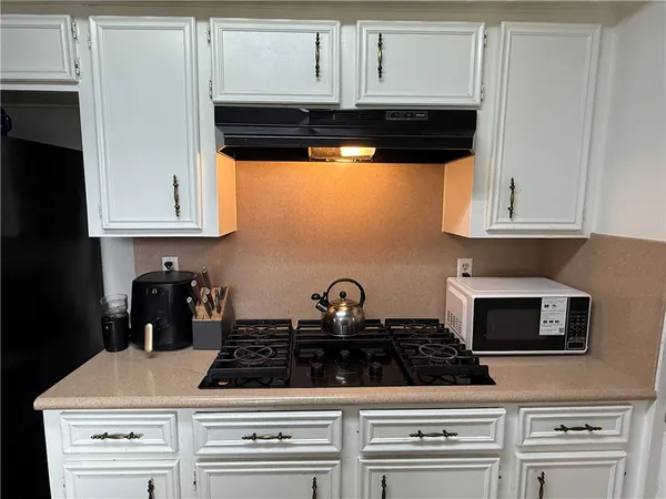 a kitchen with white cabinets and black appliances