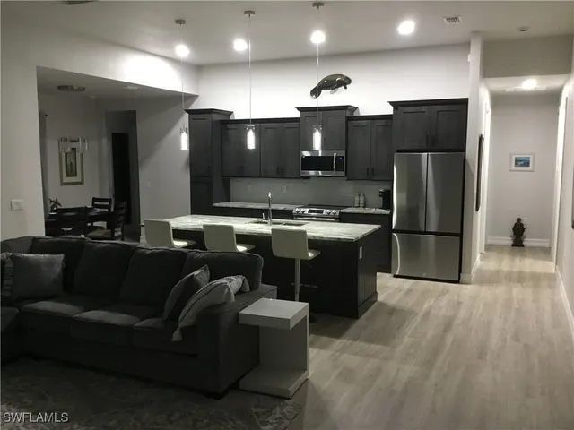 a kitchen with stainless steel appliances granite countertop a refrigerator a sink and a stove top oven