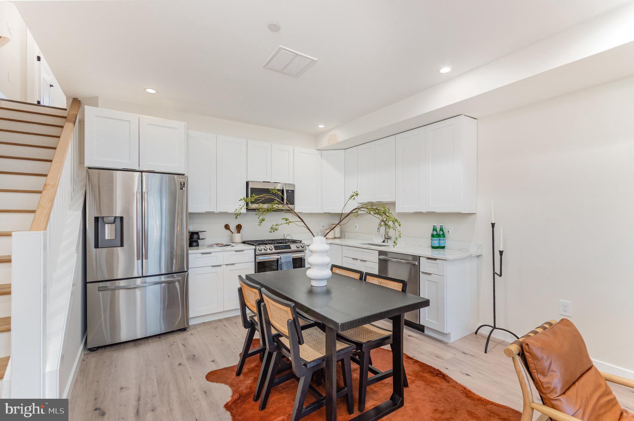 2116 4th Street Northeast, Unit B Washington, DC 20002 - Photo 8 of 28 a kitchen with stainless steel appliances a refrigerator a stove a dining table and chairs with wooden floor