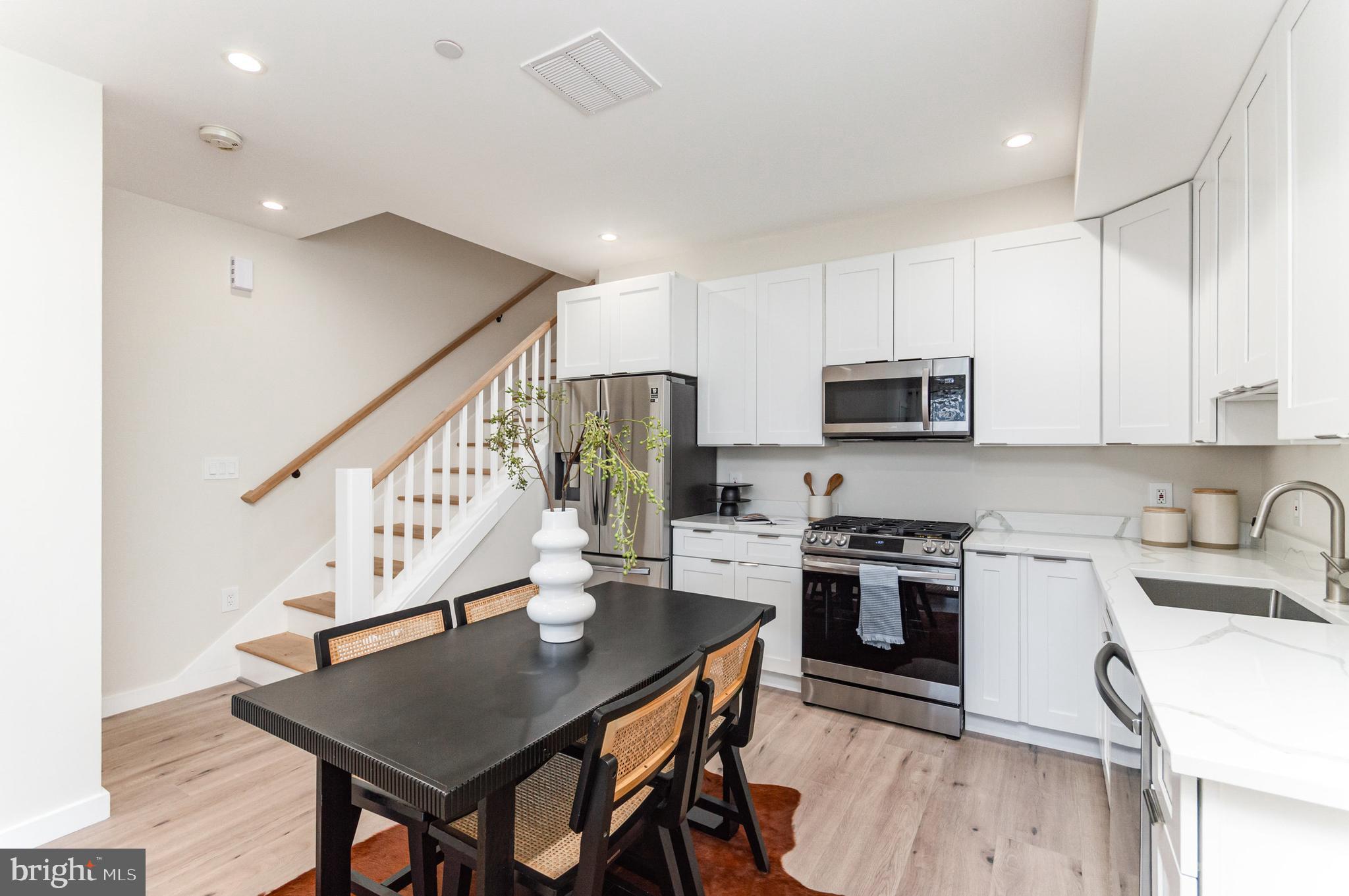 2116 4th Street Northeast, Unit B Washington, DC 20002 - Photo 9 of 28 a kitchen with stainless steel appliances granite countertop a stove top oven a sink dishwasher a dining table and chairs with wooden floor
