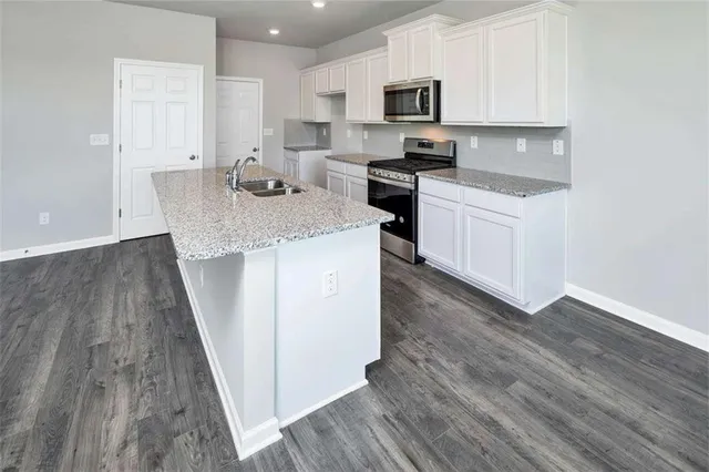 a kitchen with kitchen island granite countertop a sink stove and microwave