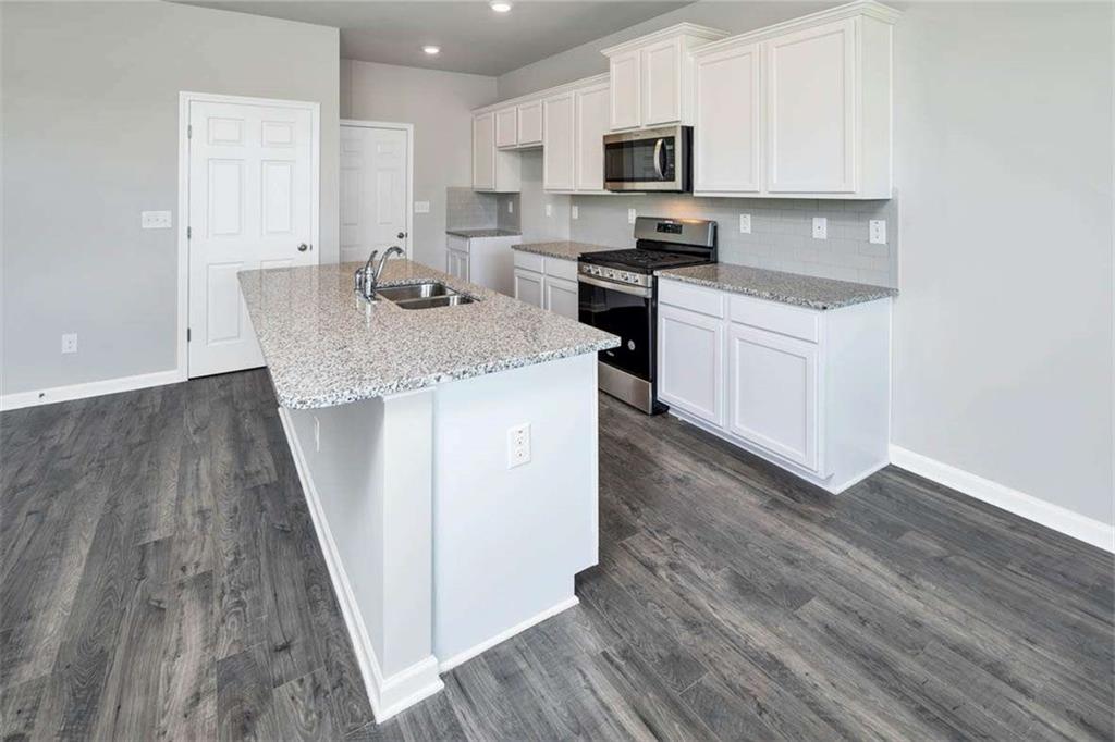 197 Lauritsen Way Newnan, GA 30265 - Photo 11 of 33 a kitchen with stainless steel appliances a white stove top oven a sink and white cabinets